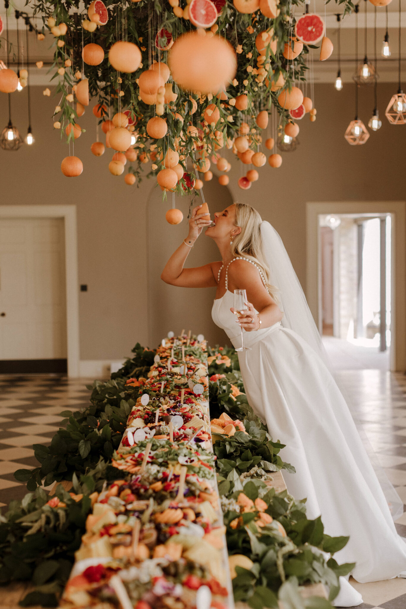 Bride at grazing table with canopy of oranges